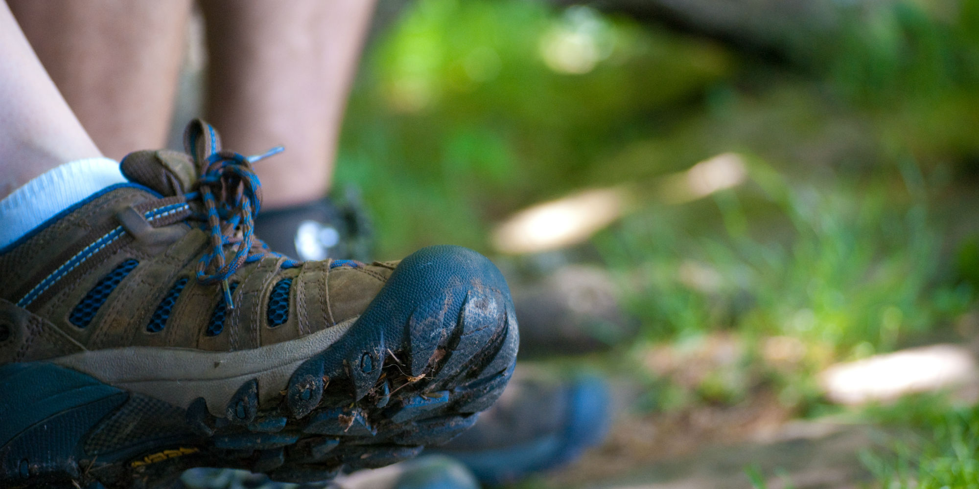 A closeup of muddy boots on a trail.