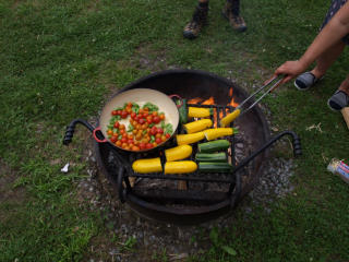 Tomatoes and summer squash roast in a dutch oven over a campfire