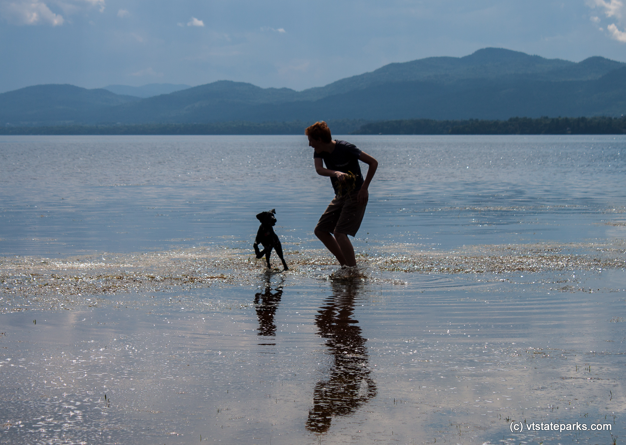 A man and his playful friend in Lake Champlain from Button Bay State Park by Tara Schatz