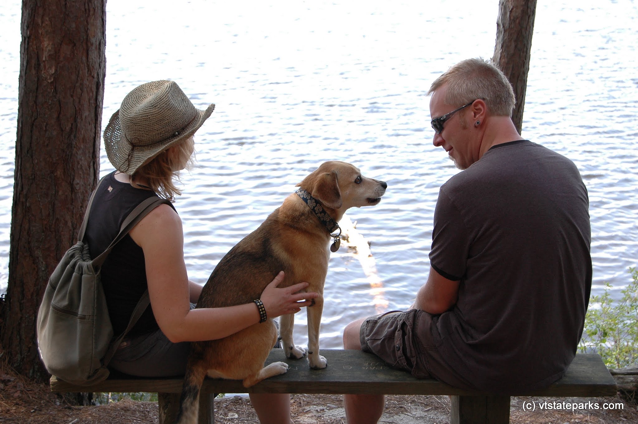 A couple and dog relax next to Spectacle Pond, Brighton State PArk