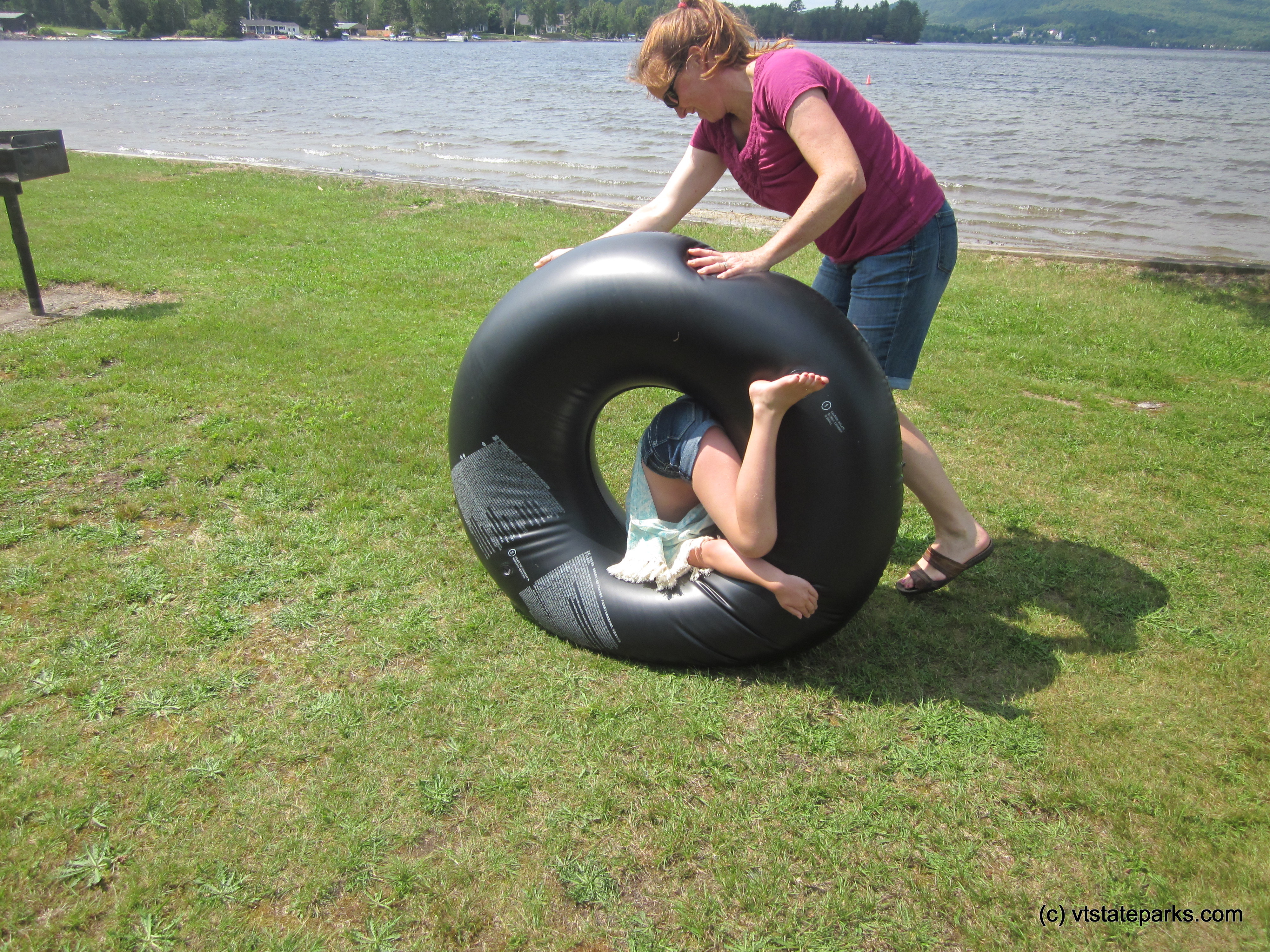 Rolling her daughter in a tube across the grass